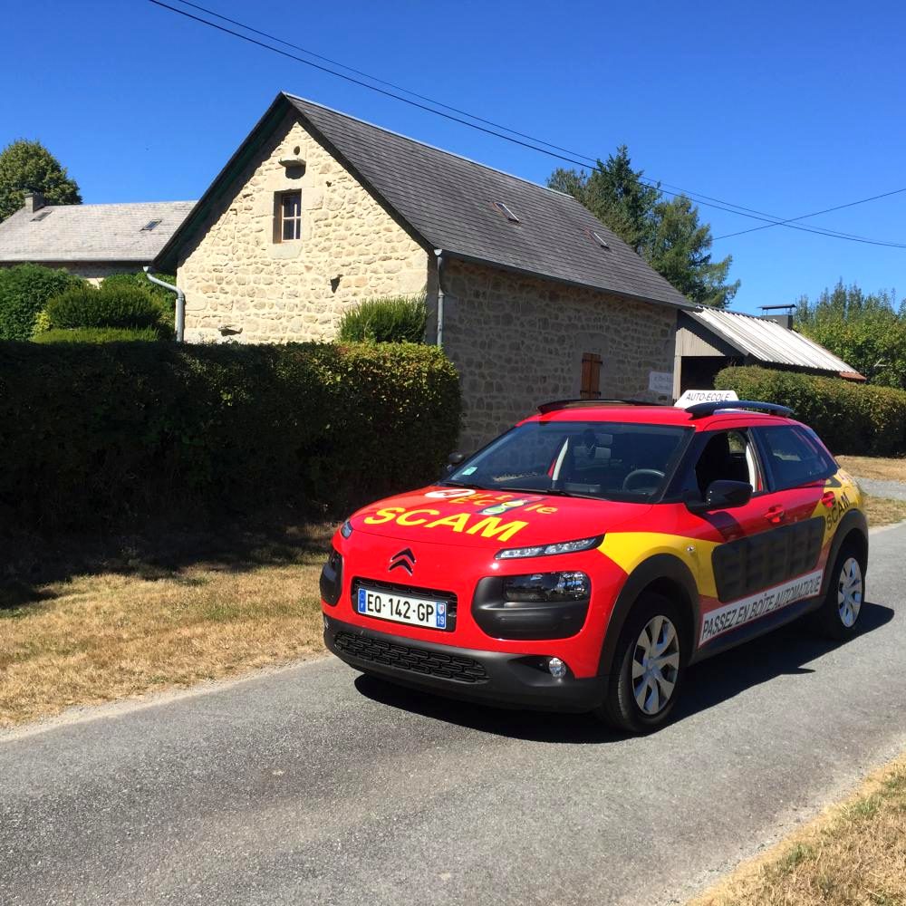 La C4 Cactus rouge et jaune de l'auto-école SCAM sur une route de campagne